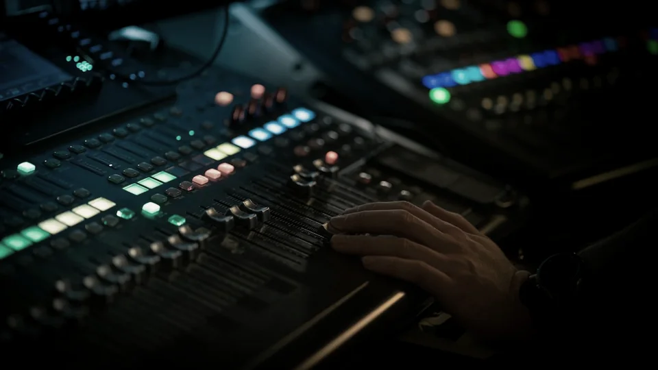 A sound engineer’s hand on the faders of a concert mixing console.