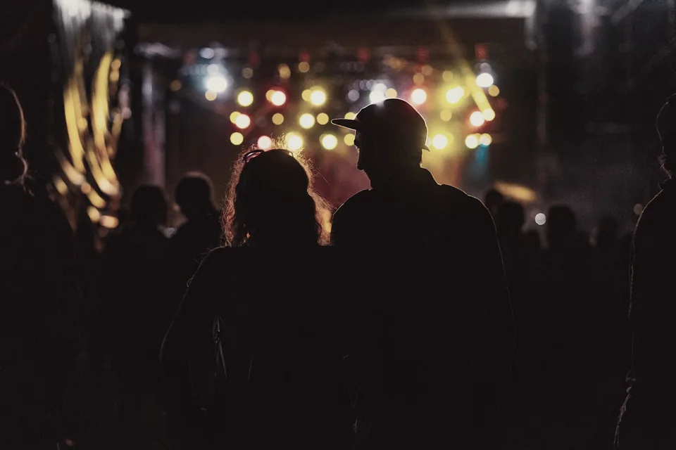 Listeners watching an illuminated concert stage.